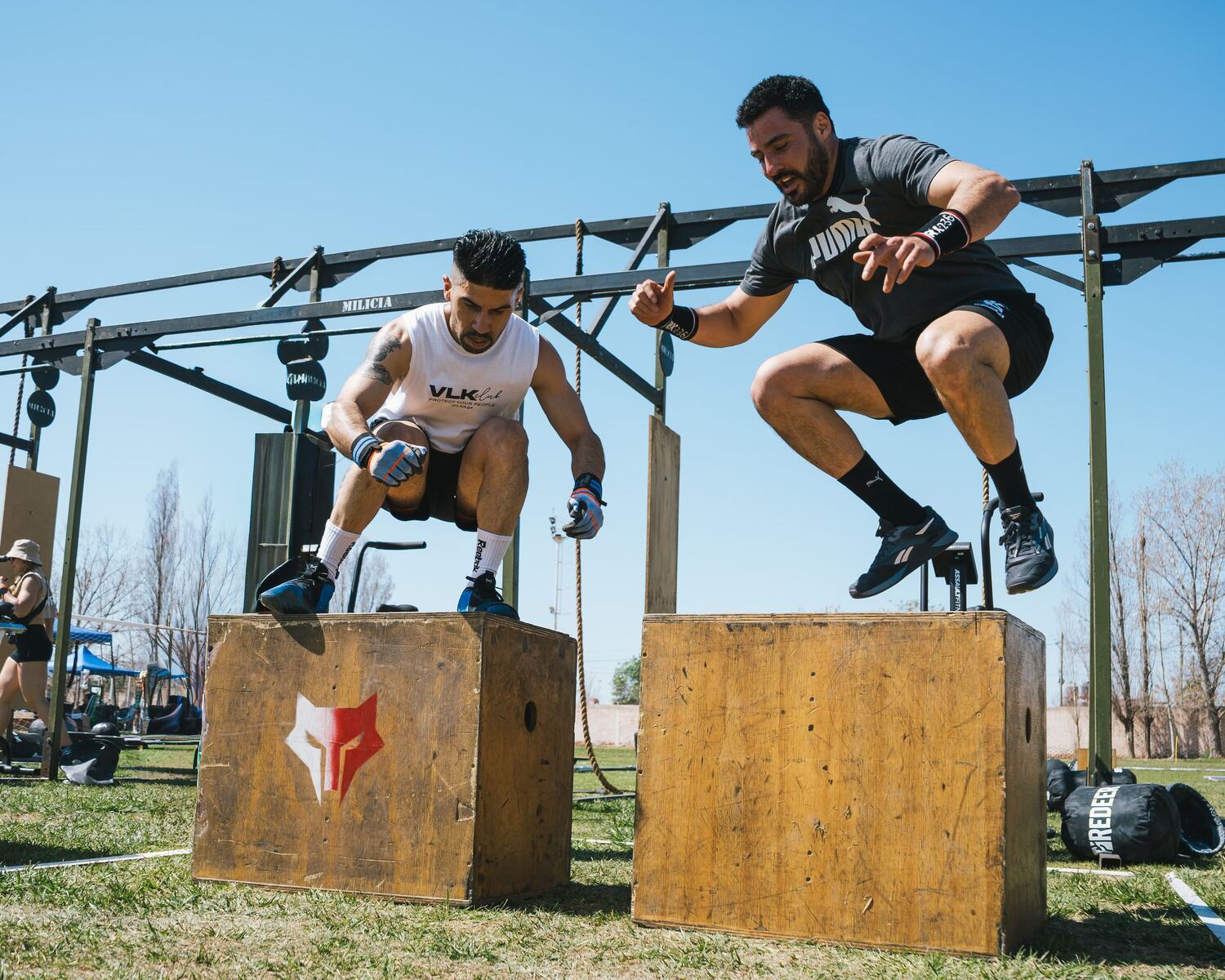 Two athletes airborne off boxes under open sky